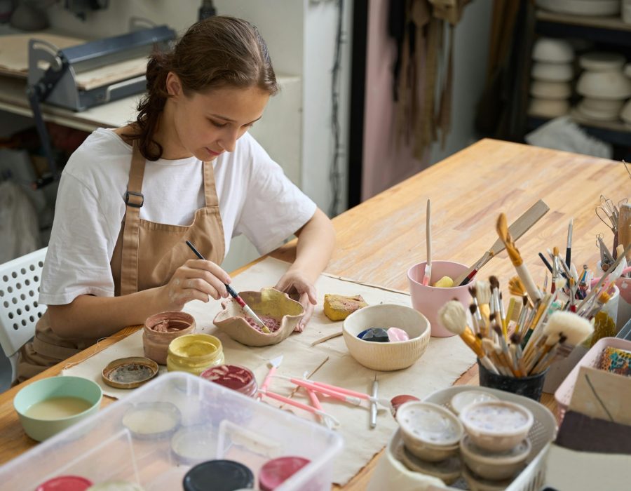 Young woman in an art workshop decorating a clay plate